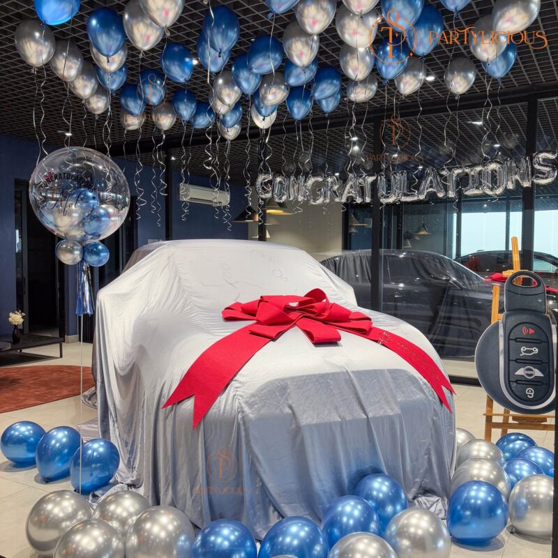 Personalised congratulations bubble balloon beside the covered car inside the showroom